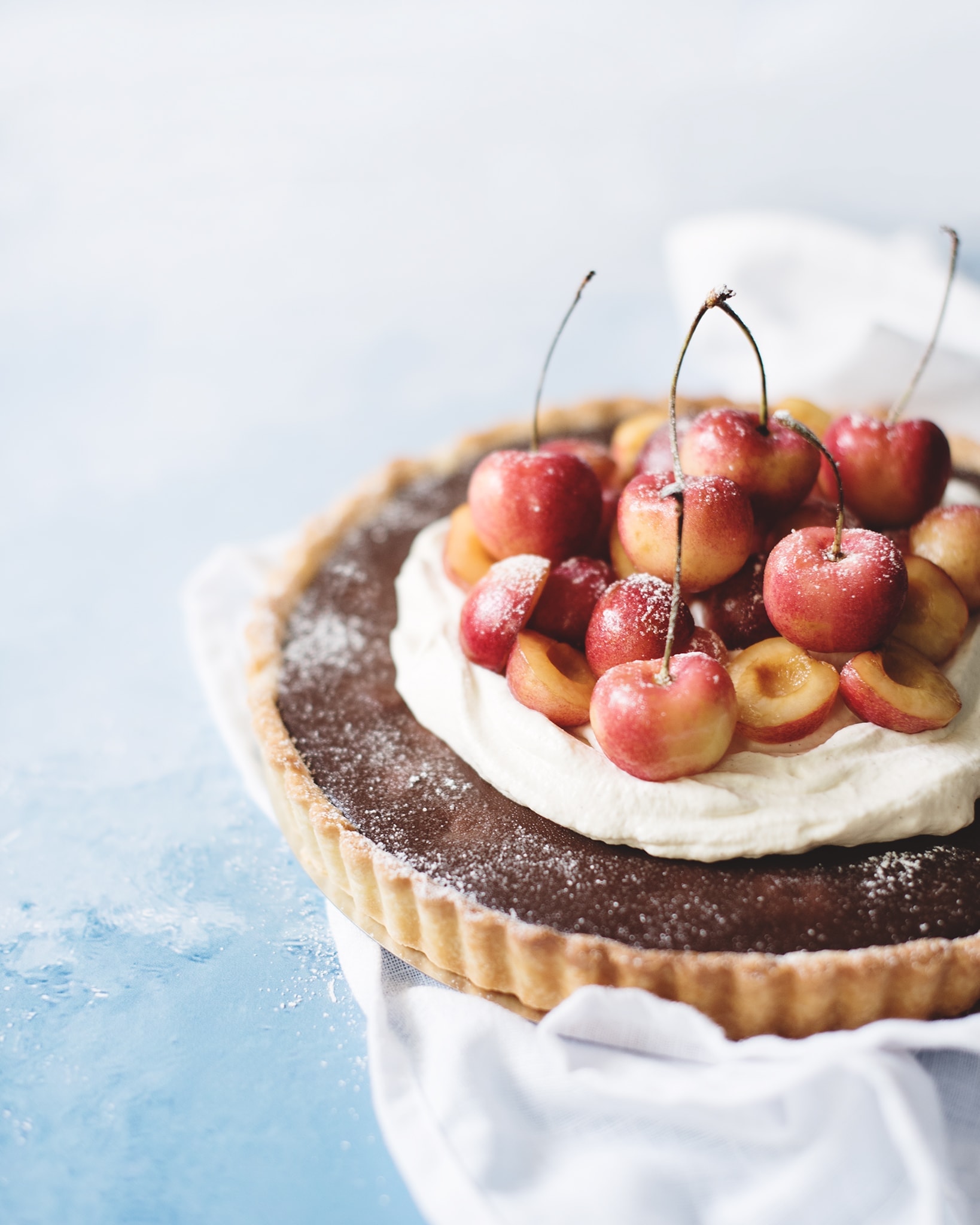 Chocolate cherry tart with cardamom cream on blue background