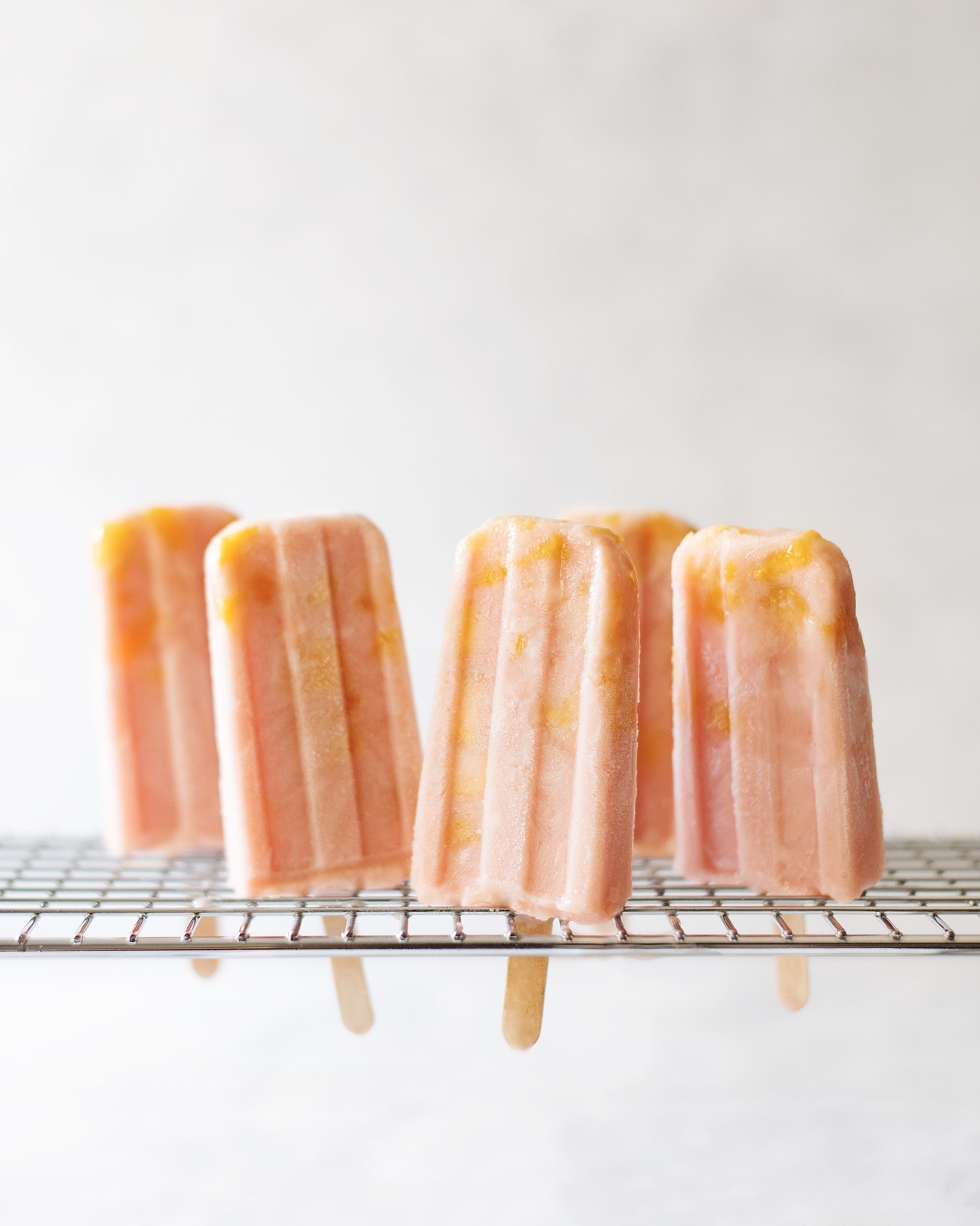 Mango guava popsicles standing up on metal rack