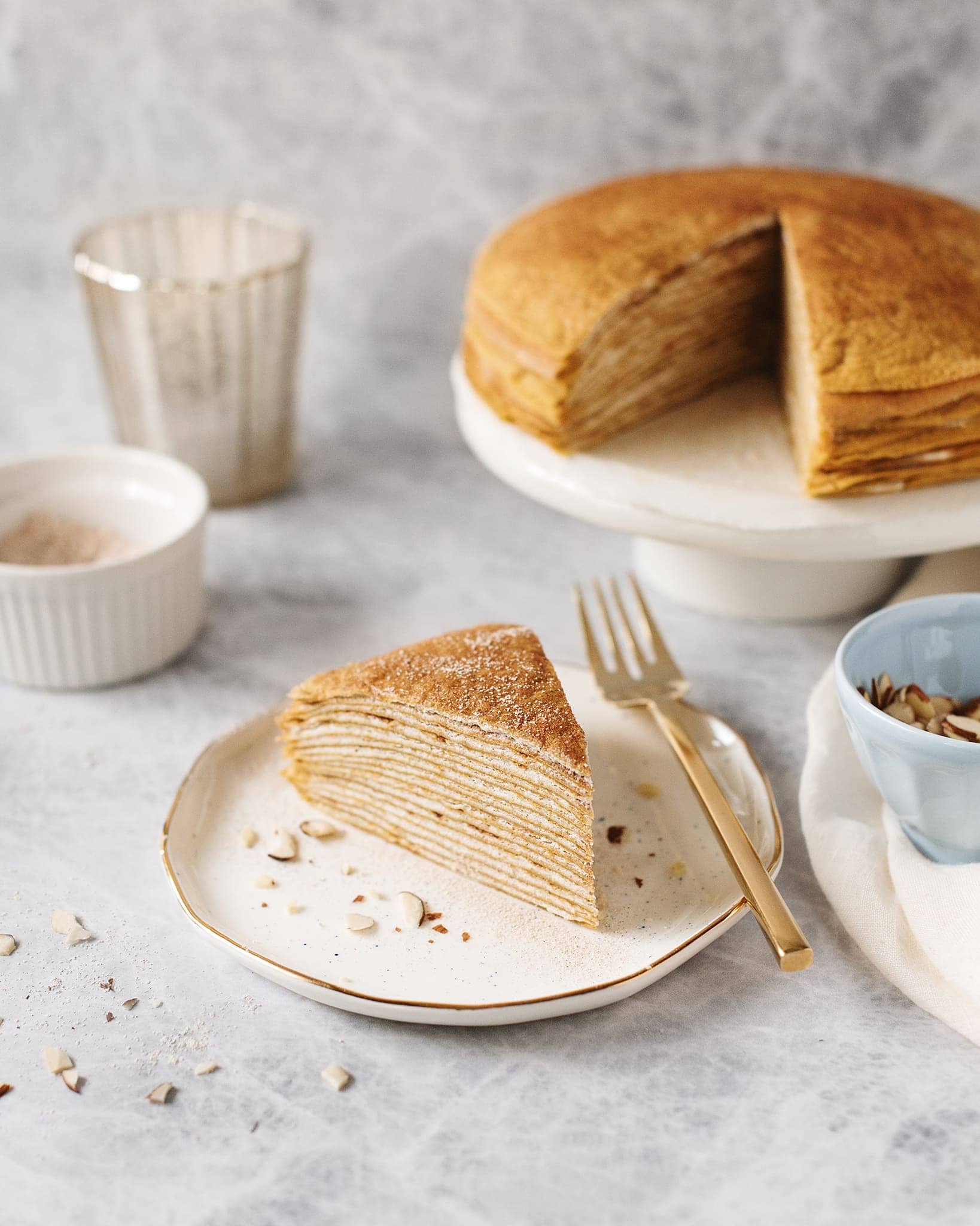 A slice cut out of a pumpkin crepe cake on a white plate