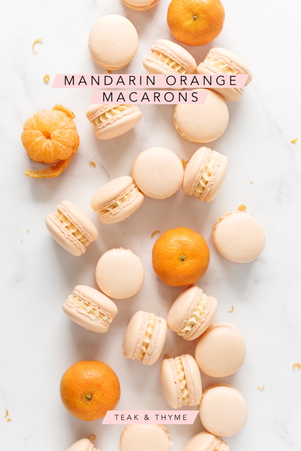 Mandarin orange macarons and mandarin oranges scattered on marble counter