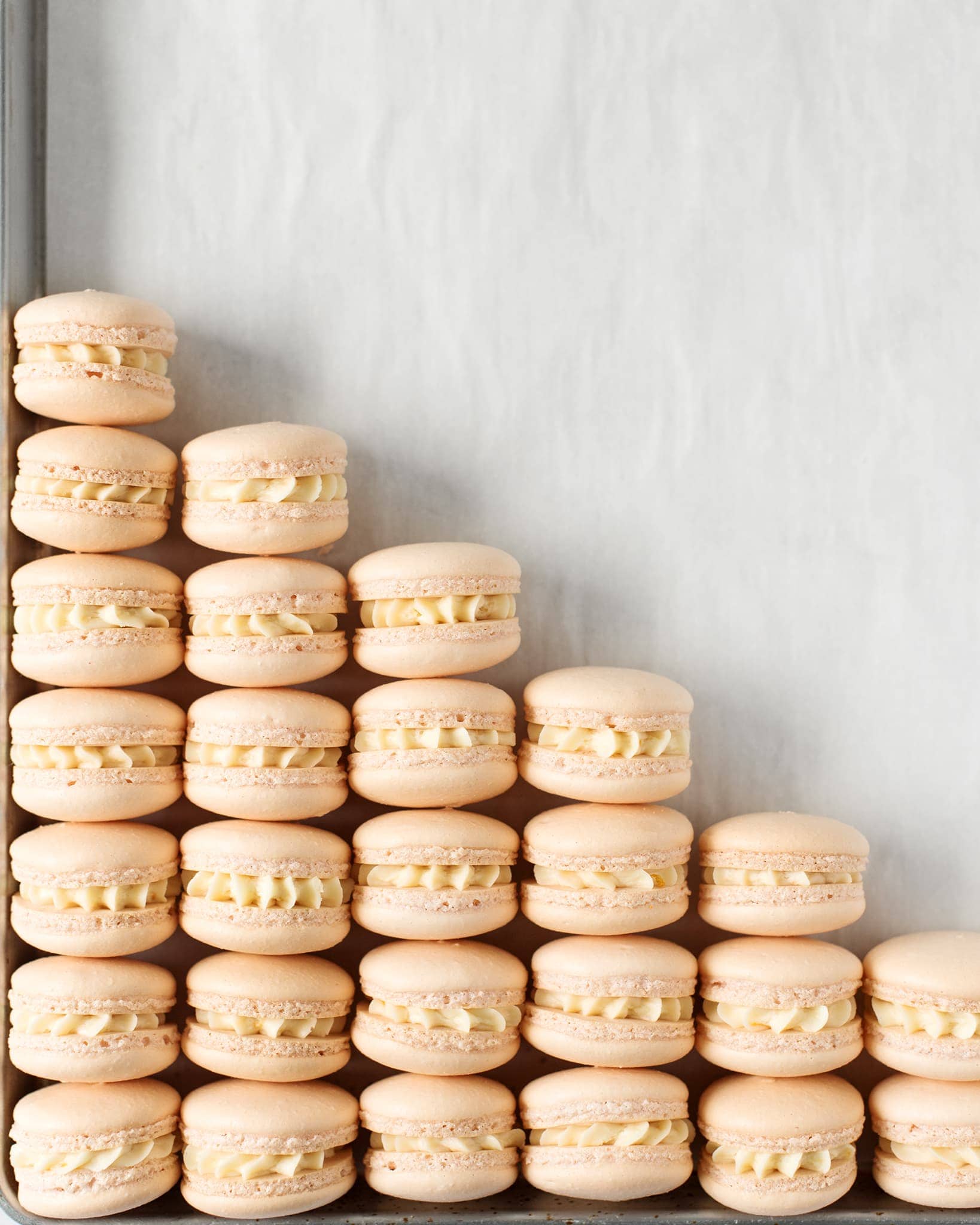 Macarons lined up in a triangle on a baking sheet