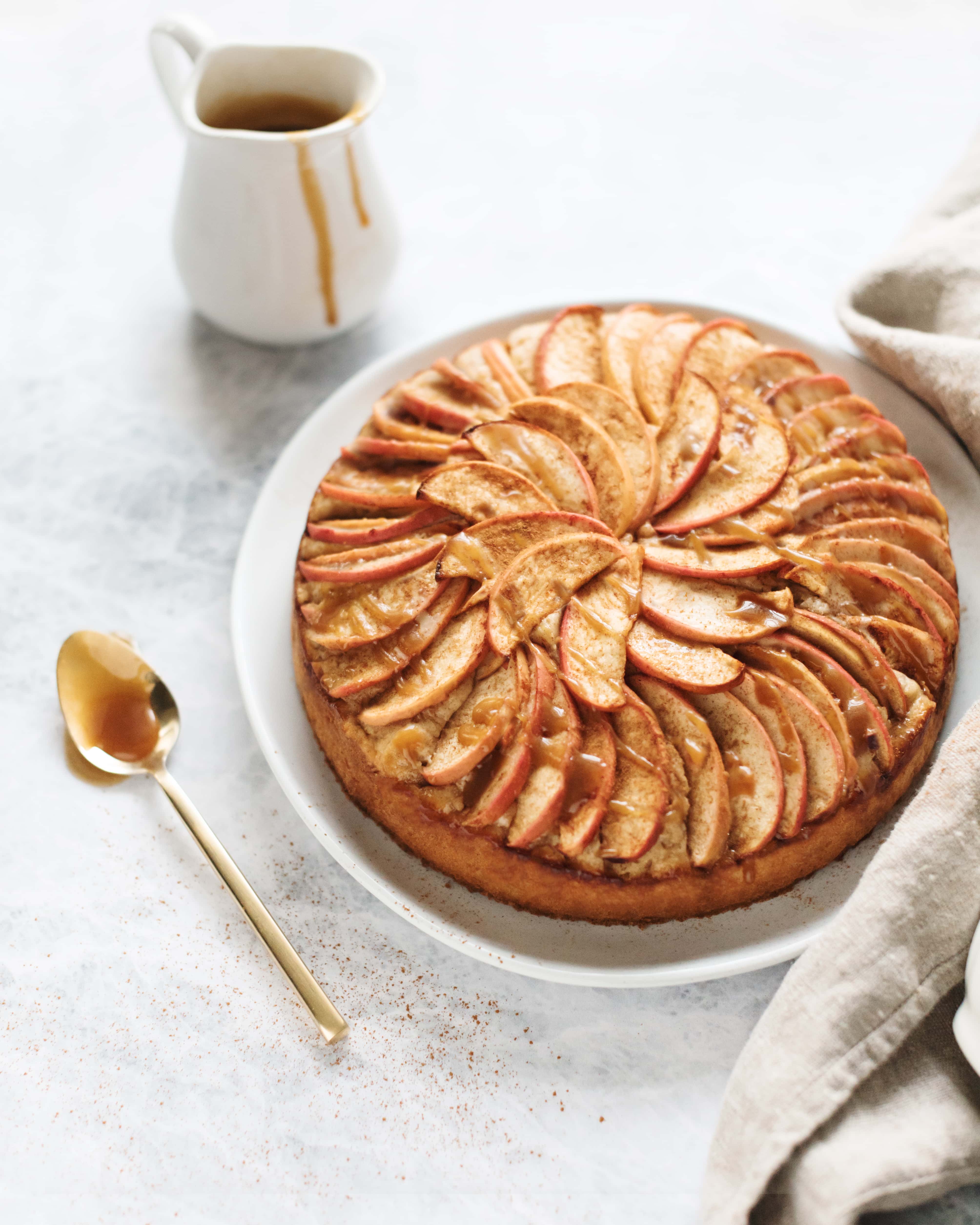 A spiced apple cake drizzled with salted maple caramel next to a spoonful of caramel