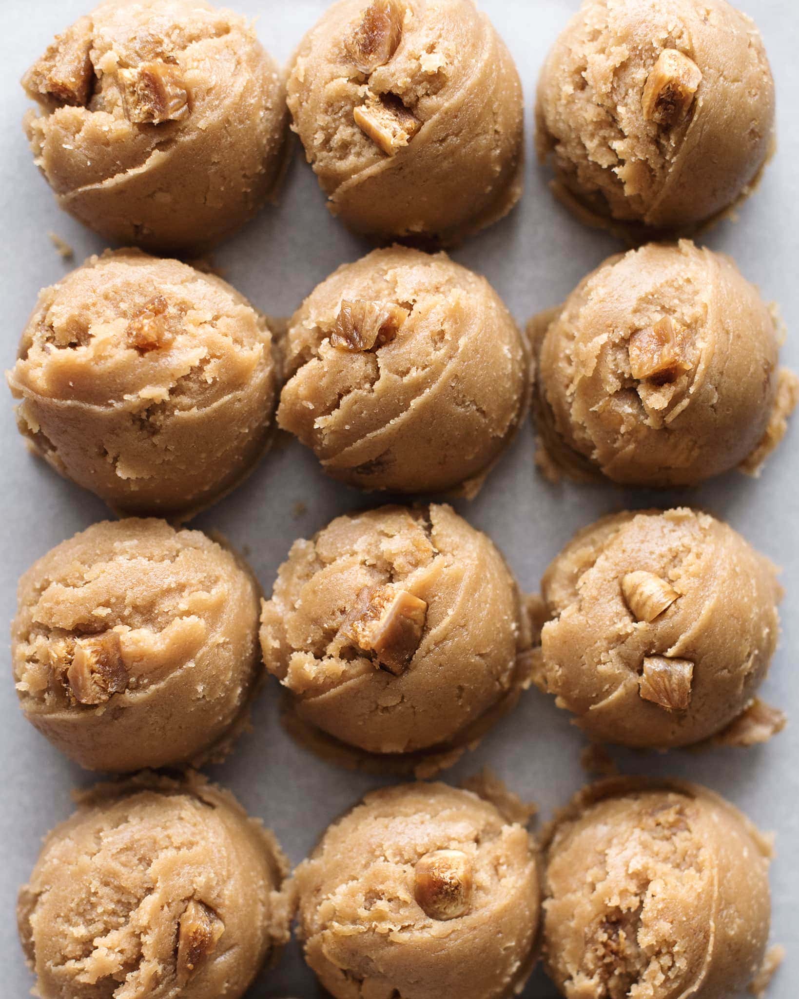 Round scoops of cookie batter lined up on a tray