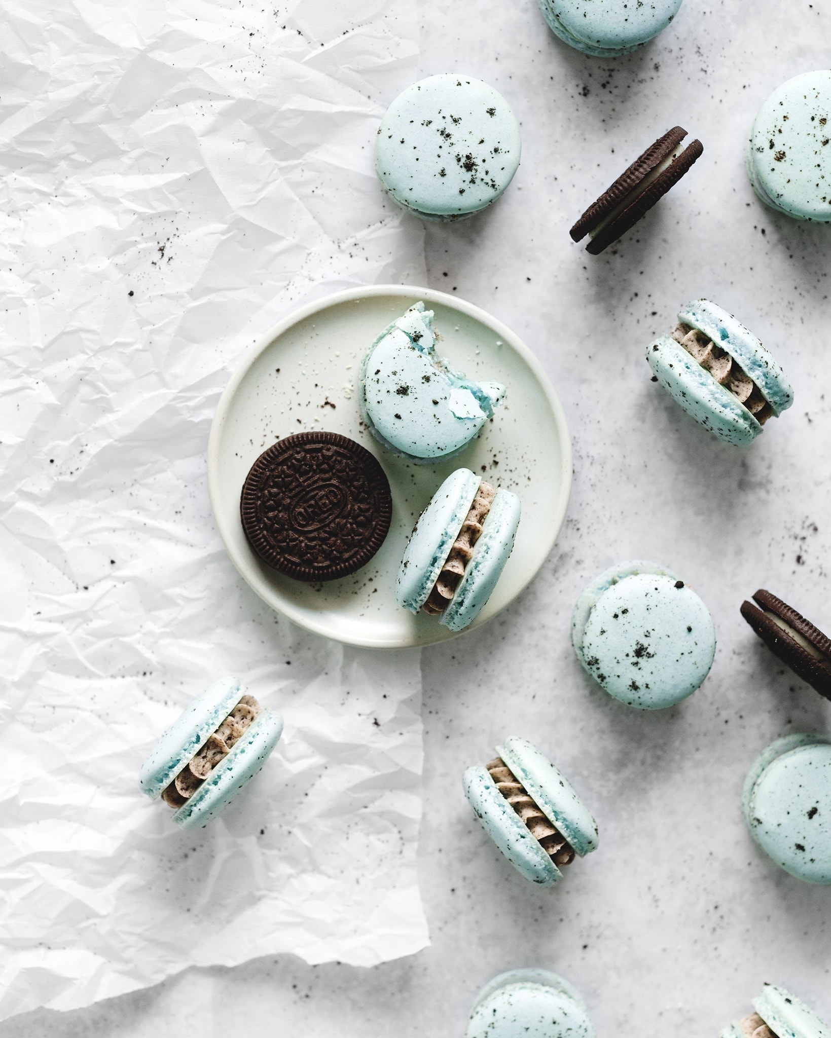 Macaron with a bite taken out of it and oreo cookies on plate