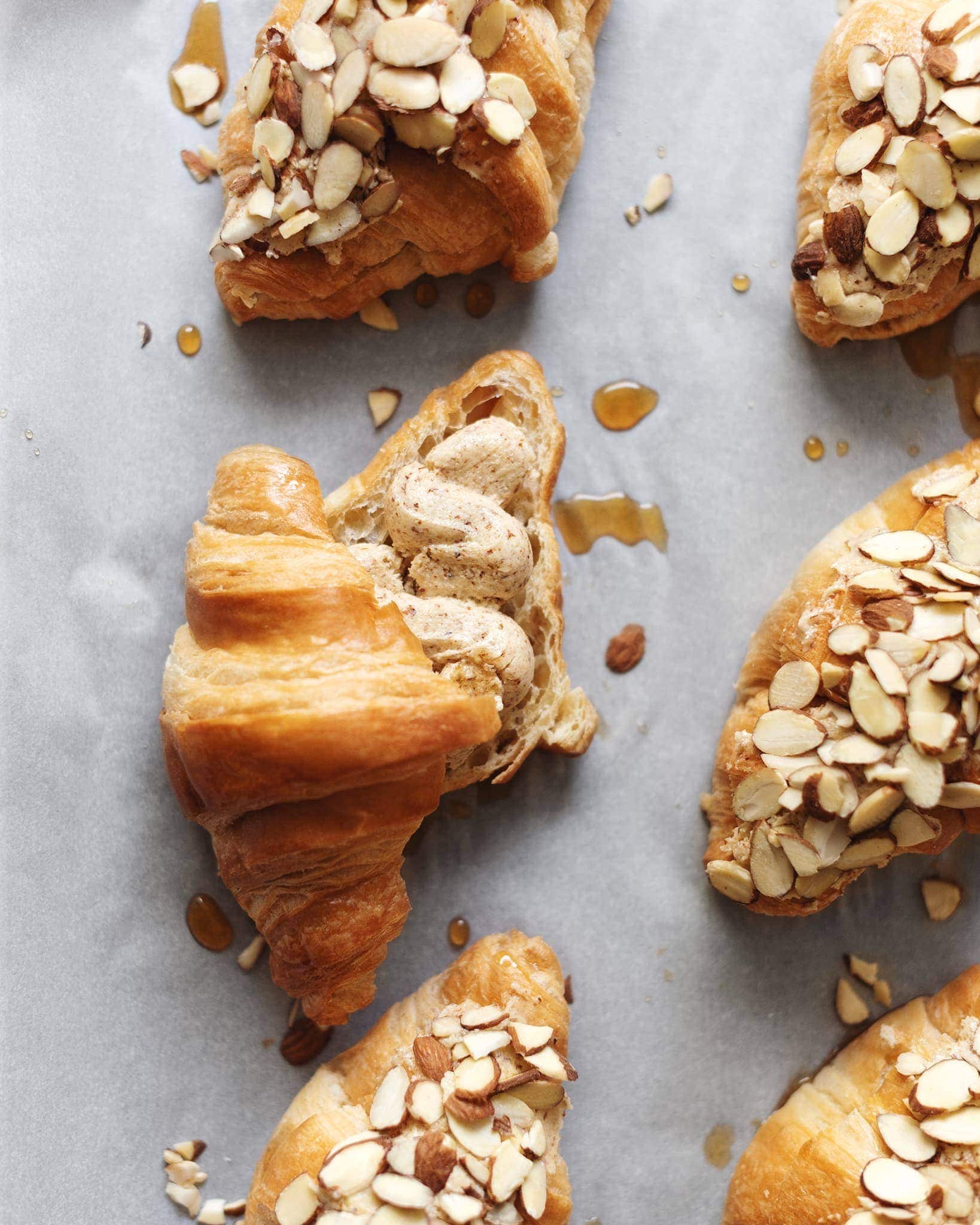 Almond croissants on baking sheet showing the frangipane filling inside