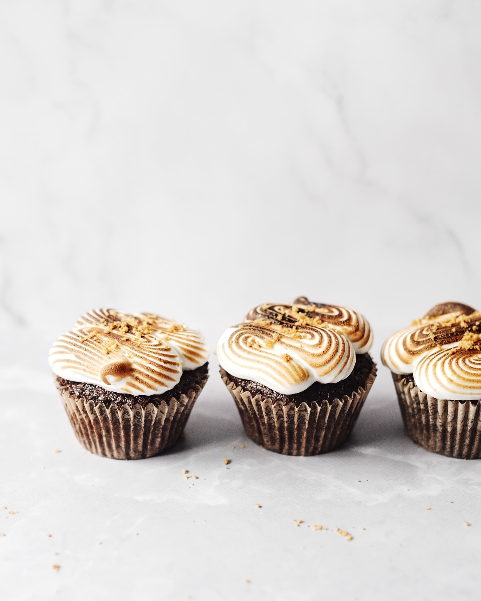 Two s'mores cupcakes on grey background