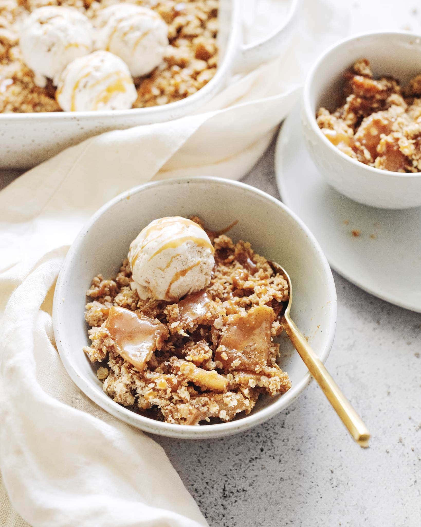Bowls of caramel apple crisp topped with scoop of ice cream