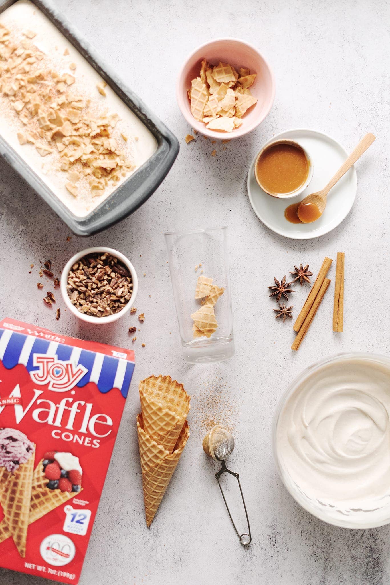 Glass surrounded by ingredients for waffle cone ice cream parfait