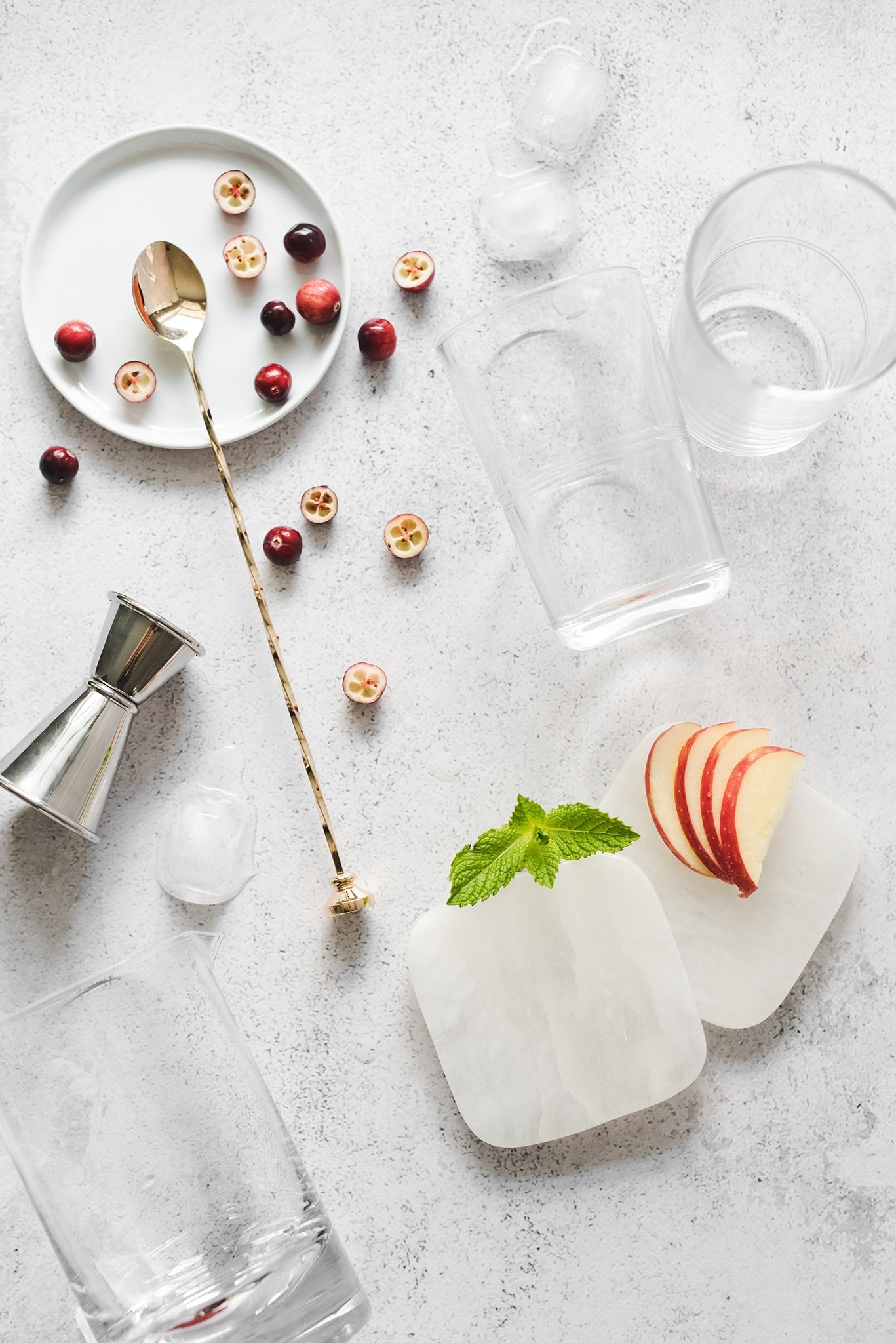 Glasses, coasters, and ingredients for cranberry apple mojitos