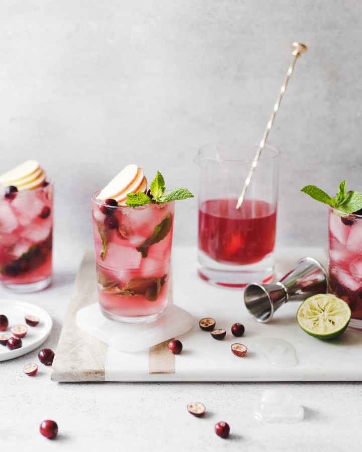 Cranberry apple mojitos on a marble and wood serving tray