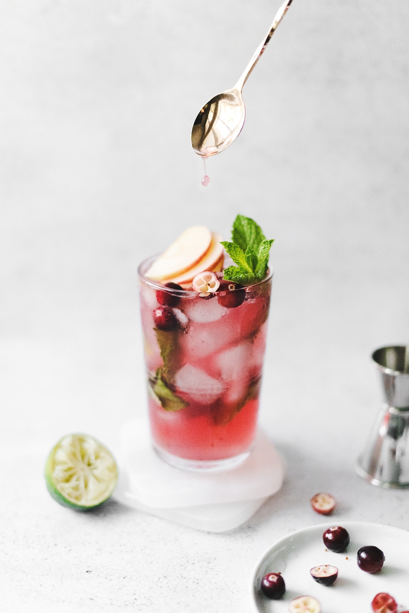 Juice dripping from gold spoon into a cranberry cocktail