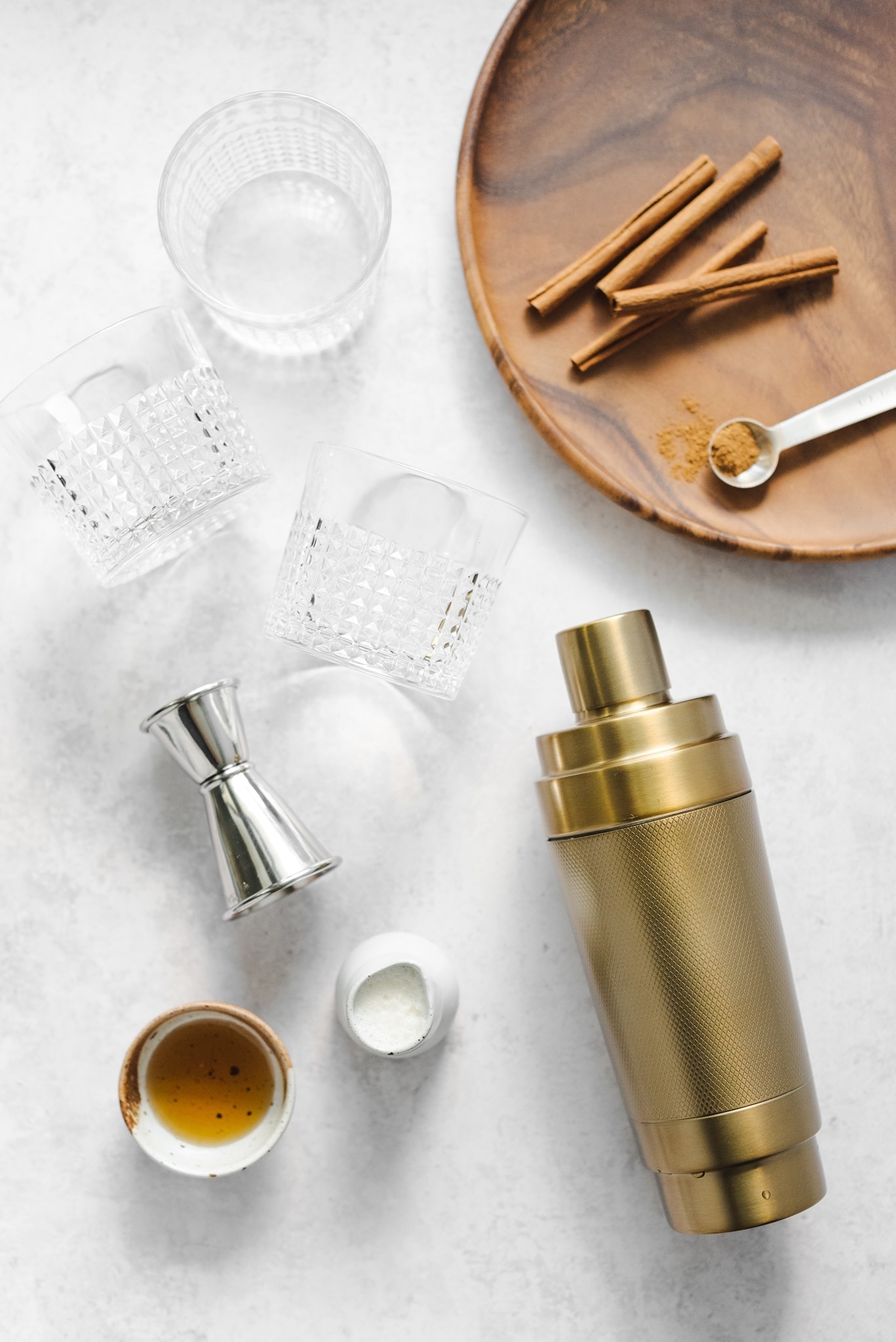 Glasses, jigger, and cocktail shaker on grey background