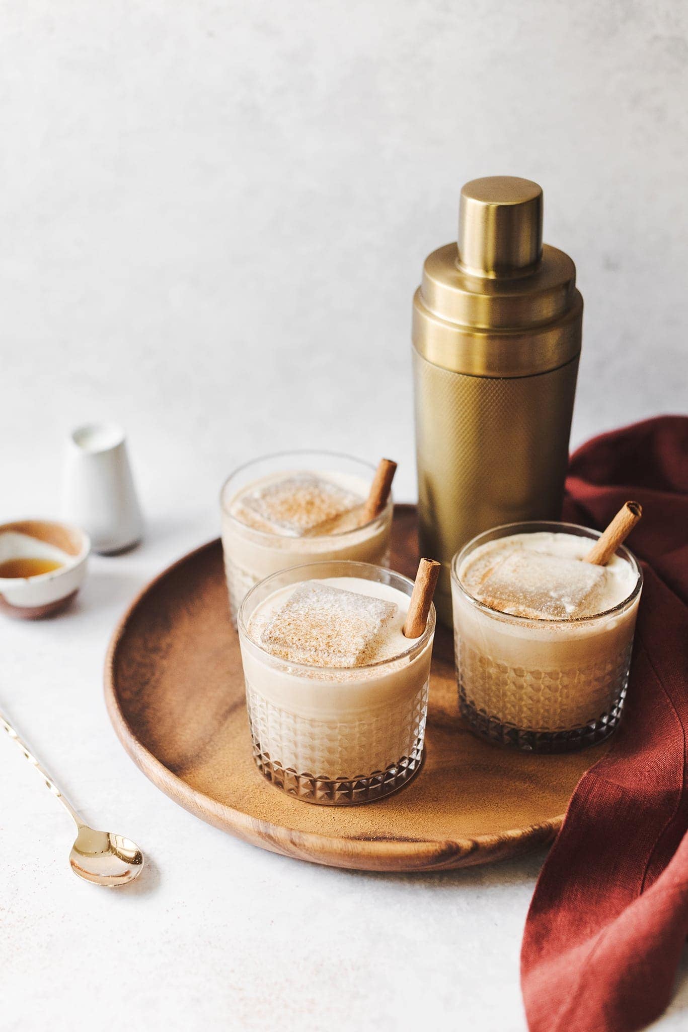 Pumpkin spice white russian cocktails and gold cocktail shaker on wood platter