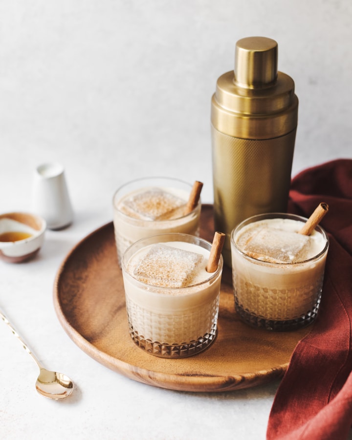 Pumpkin spice white russian cocktails and gold cocktail shaker on wood platter