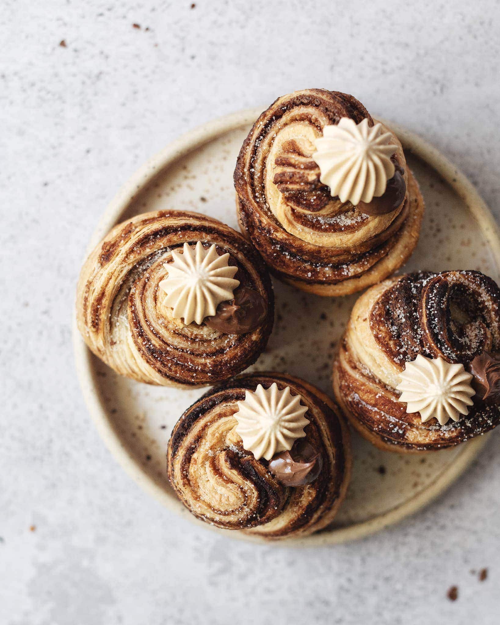 Plate of four nutella cruffins topped with dollops of whipped cream and nutella