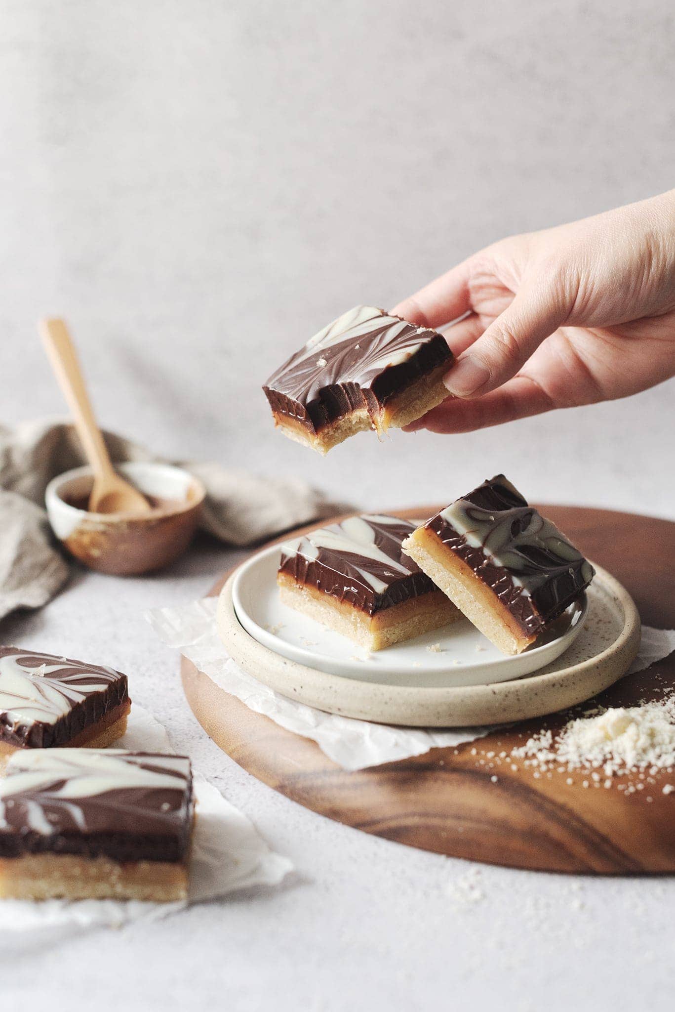 Hand holding millionaire's shortbread bar with bite taken out of it