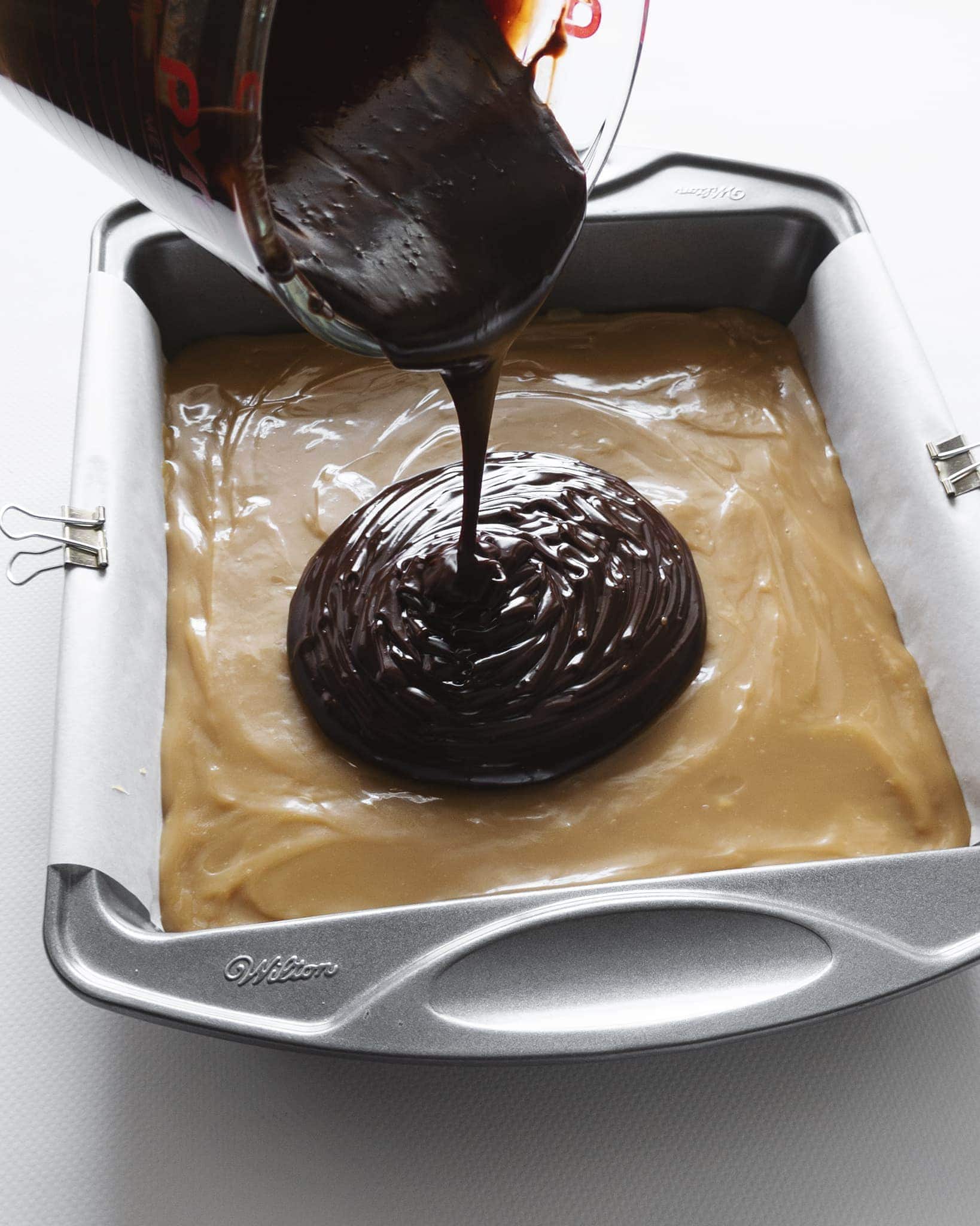 Pouring chocolate ganache on top of caramel layer