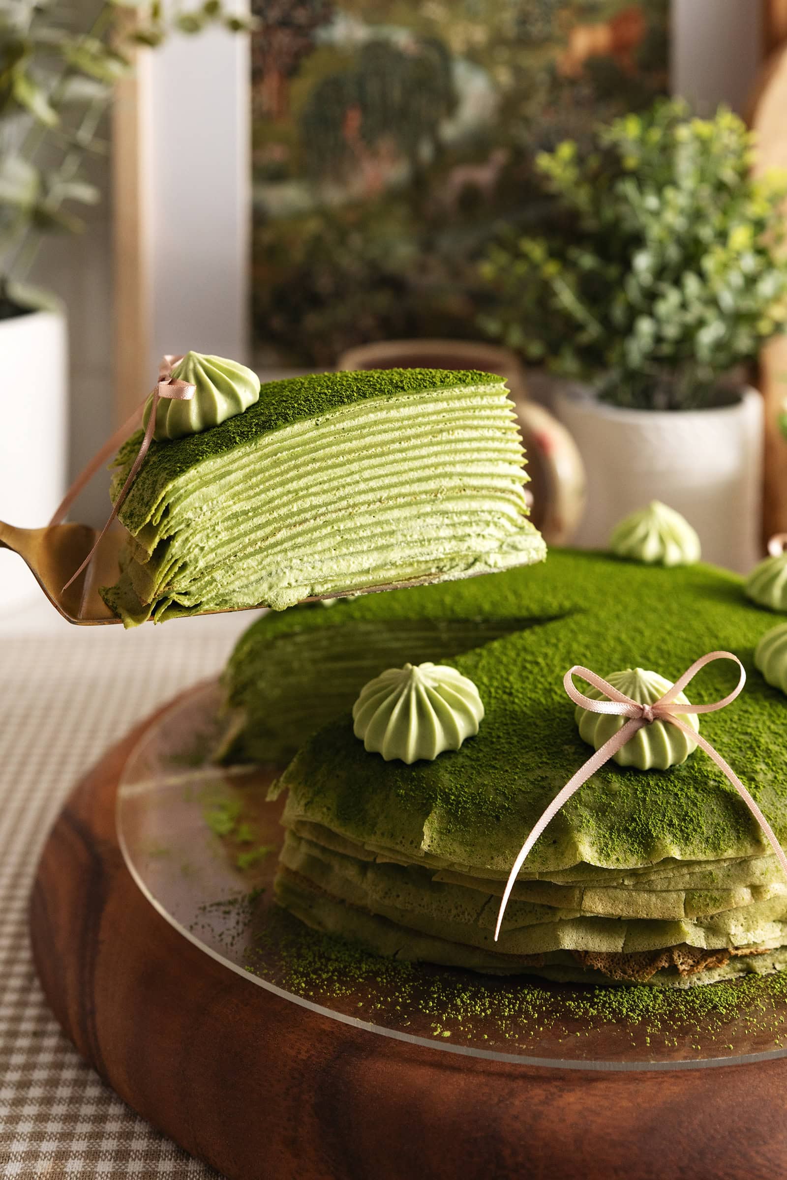 A slice of matcha crepe cake lifted above the rest of the cake to show the many layers.