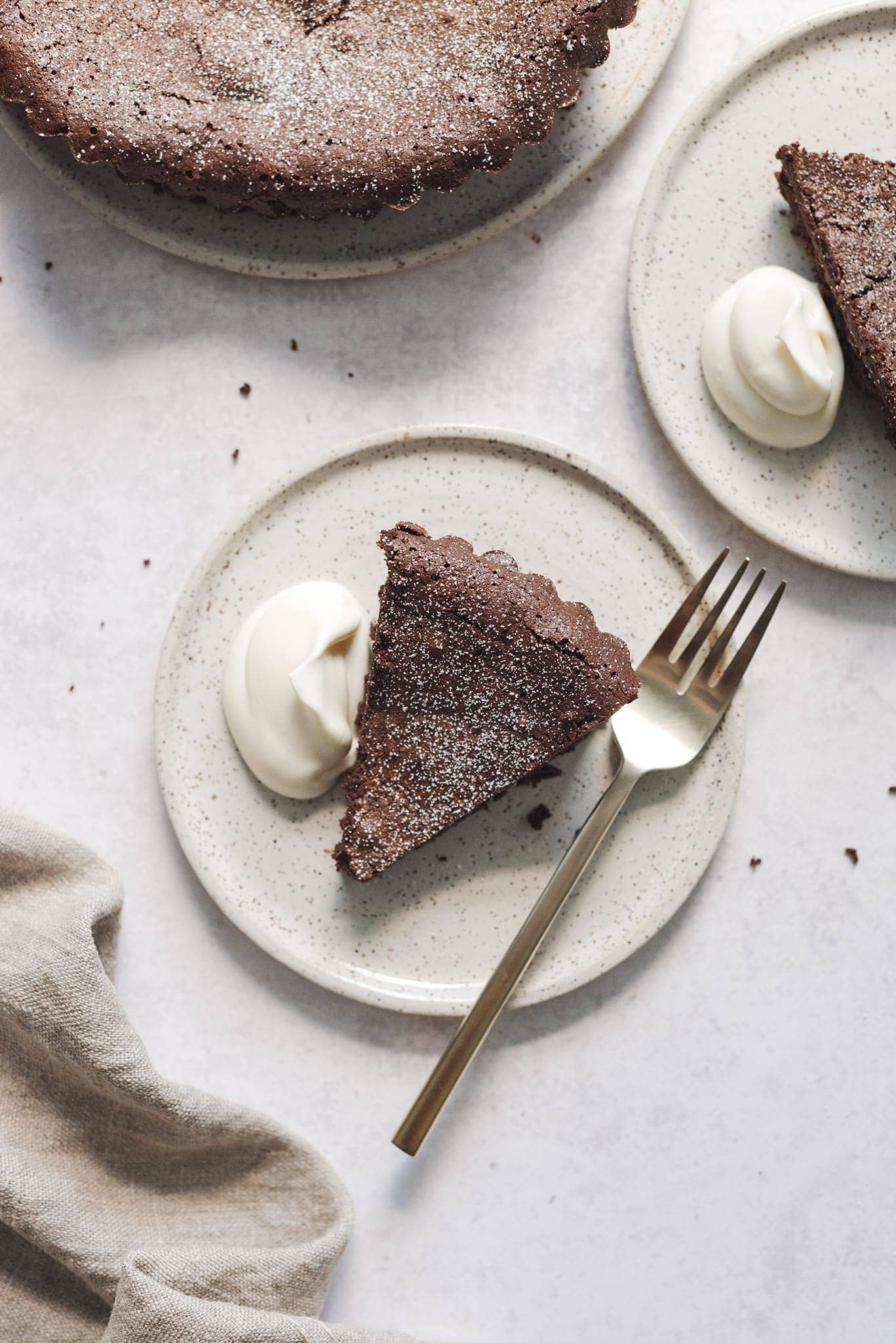A slice of flourless chocolate cake on a plate with whipped cream