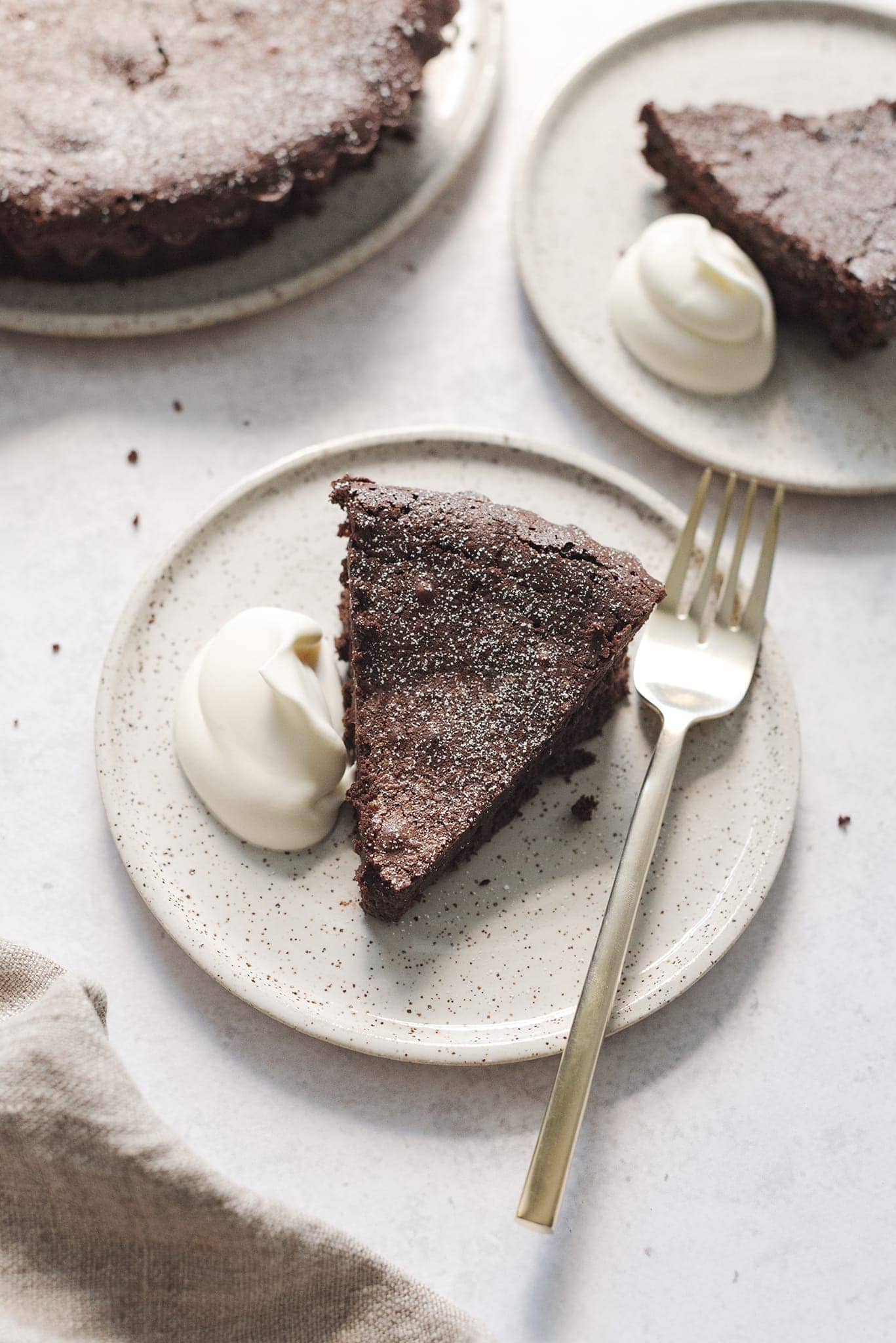 A slice of flourless chocolate cake on a plate with whipped cream