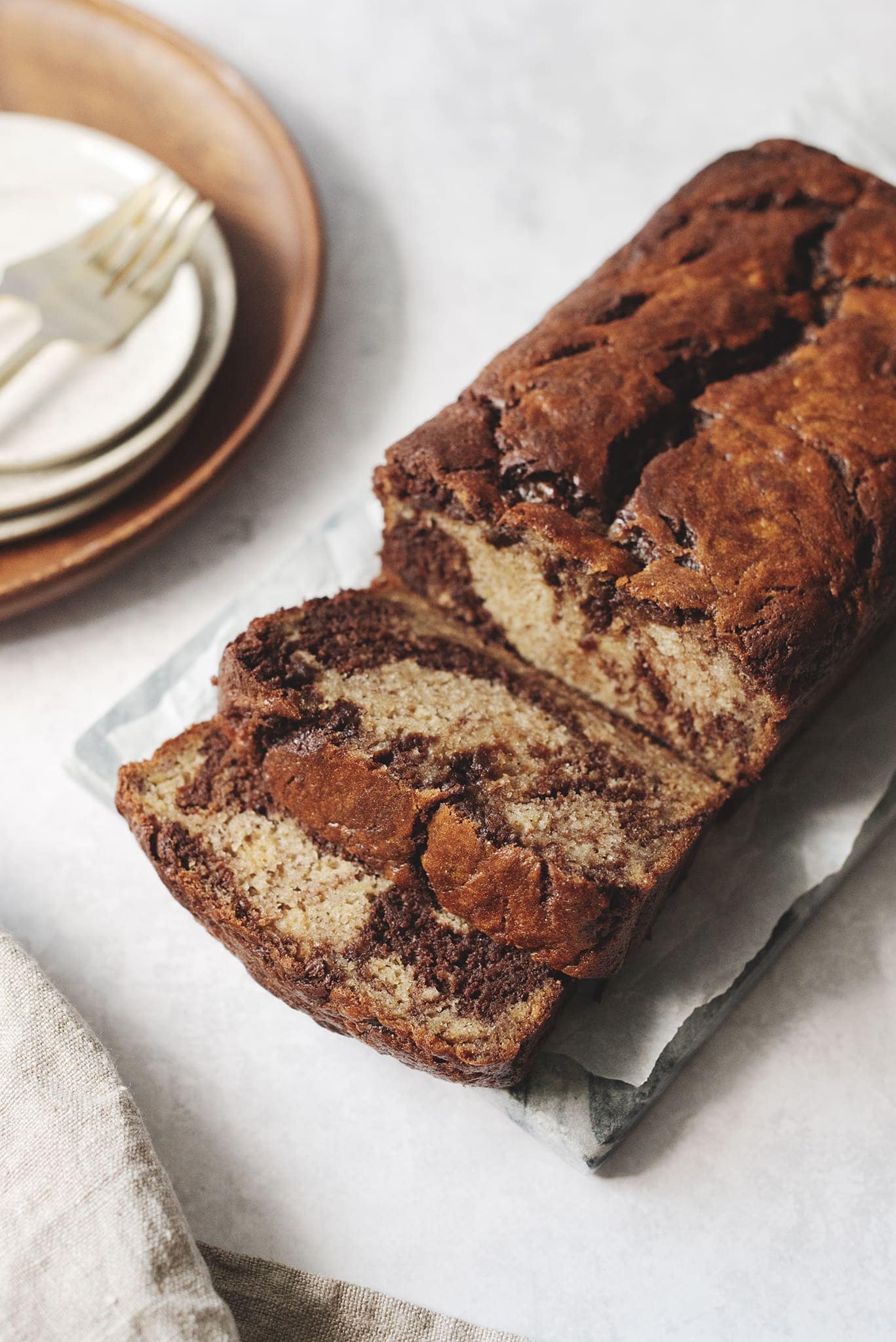 Slicing chocolate swirl banana bread form the loaf