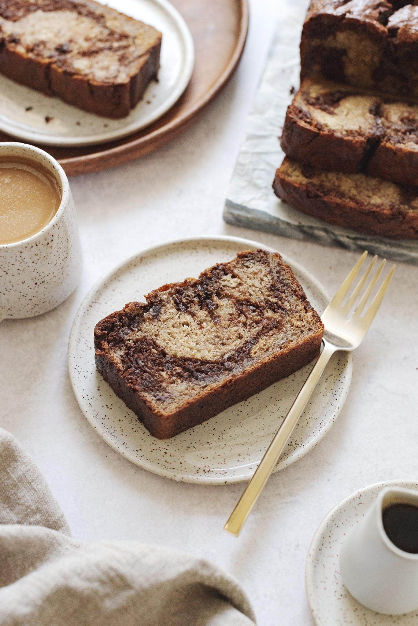 A slice of banana bread on speckled plate with fork