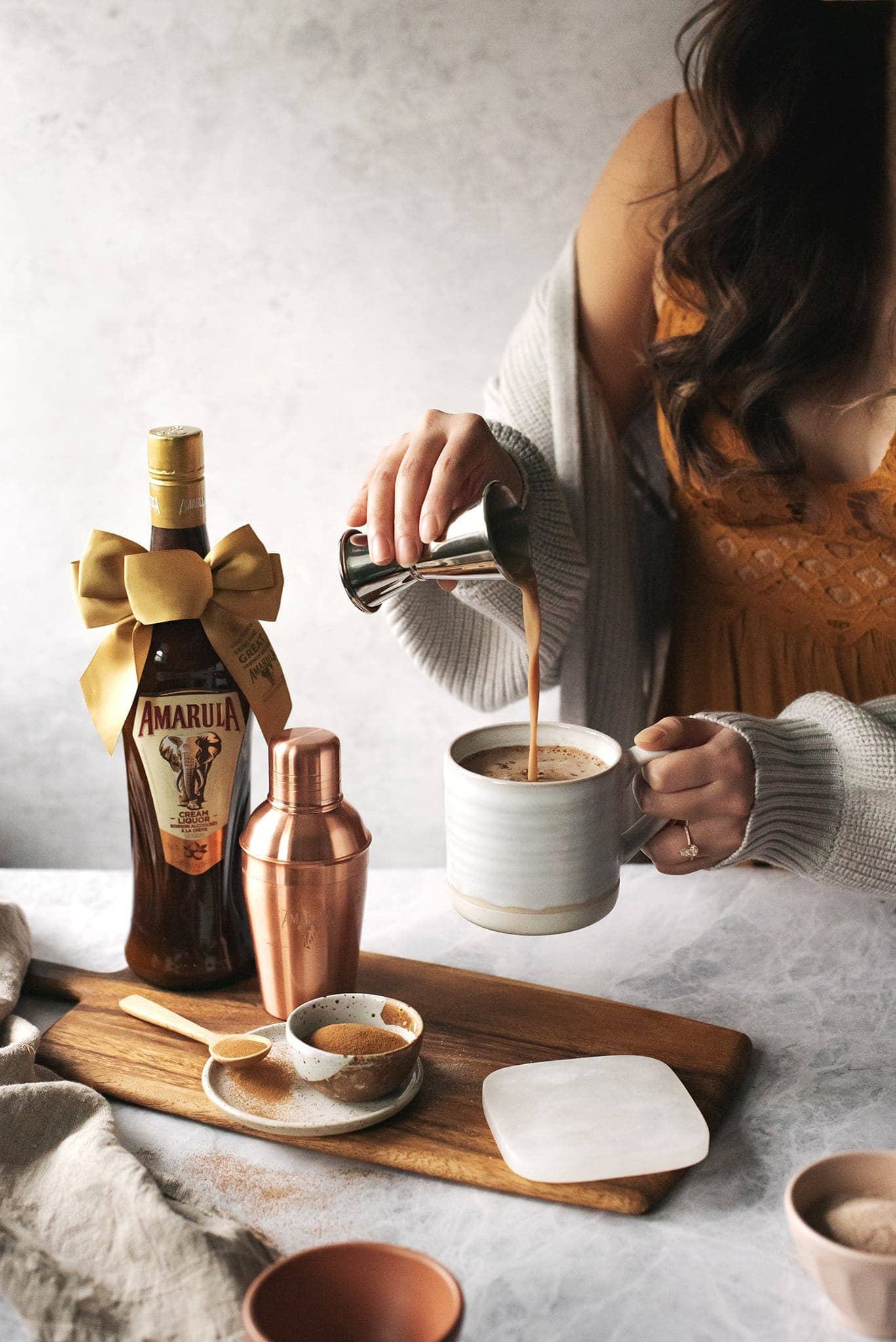 Pouring Amarula cream liqueur into a mug of hot chocolate and coffee