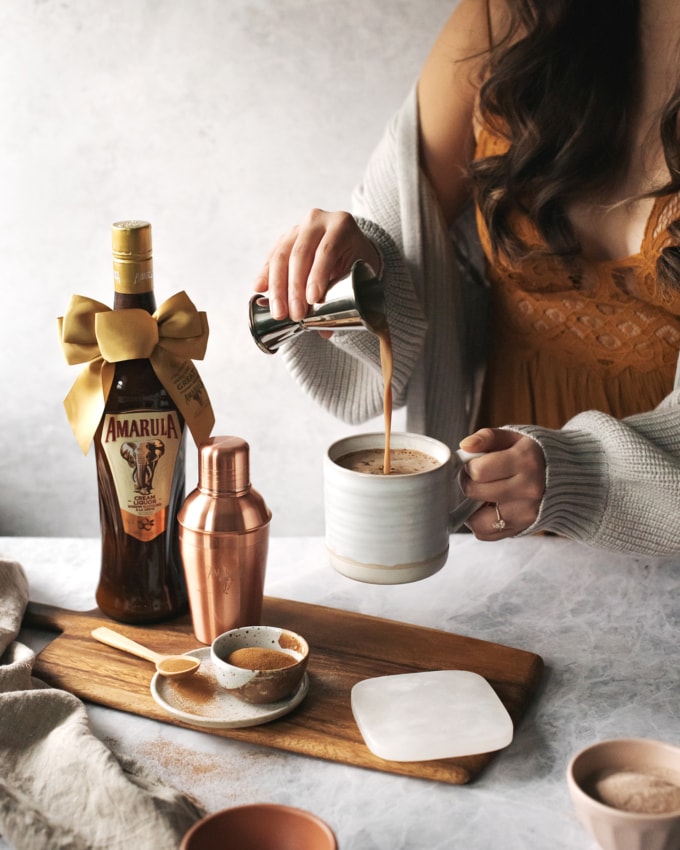 Pouring Amarula cream liqueur into a mug of hot chocolate and coffee
