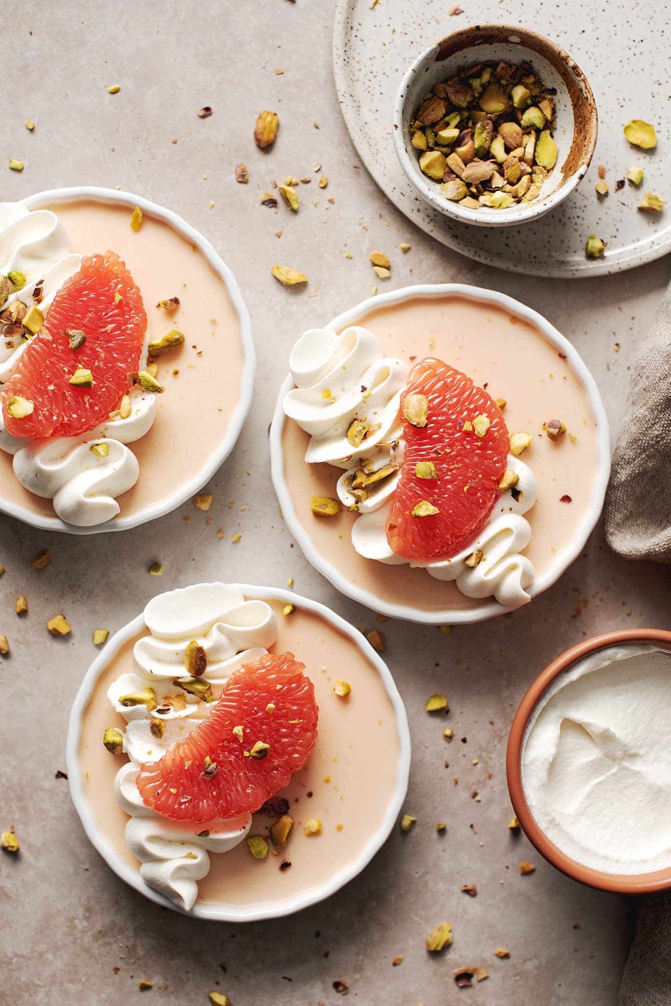 Three panna cottas with whipped cream and grapefruit slices