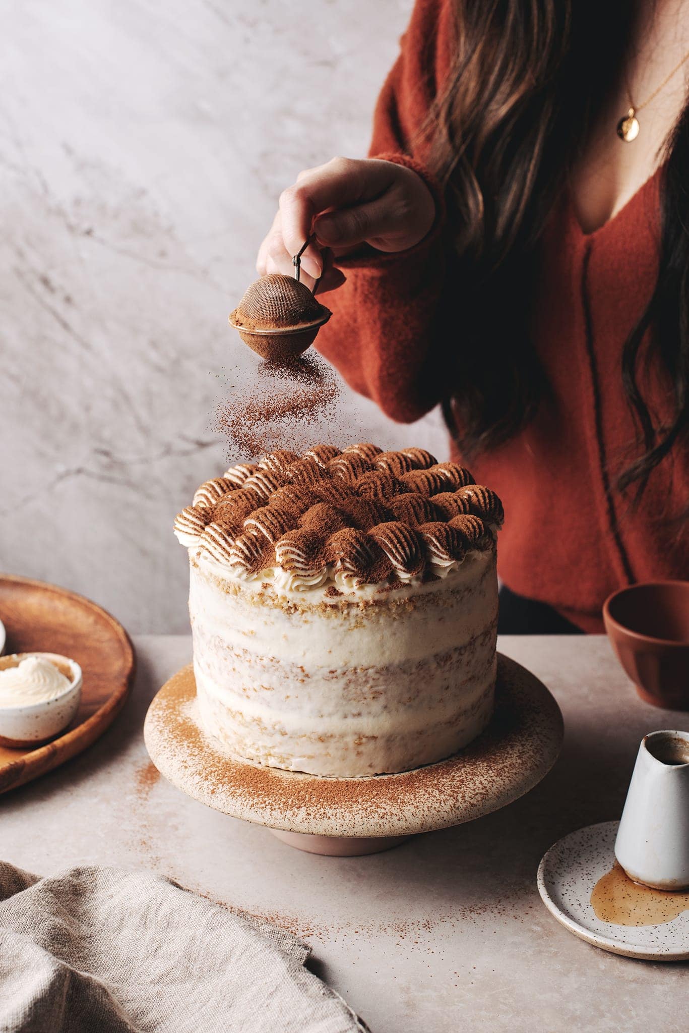 Dusting the top of tiramisu cake with cocoa powder