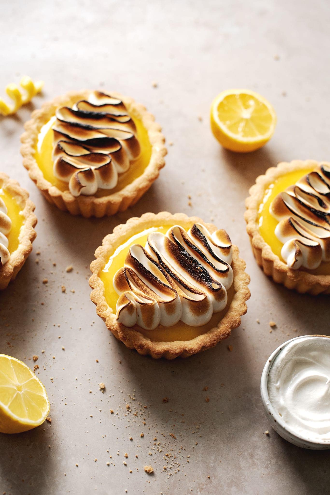Piped squiggle design of toasted meringue on top of lemon tarts