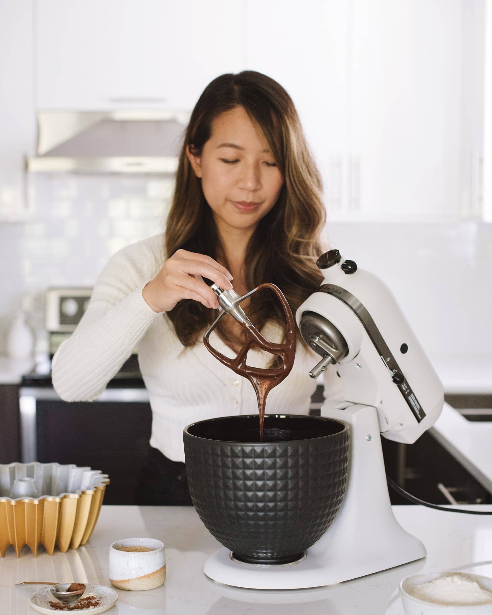 girl holding paddle of stand mixer with batter dripping off