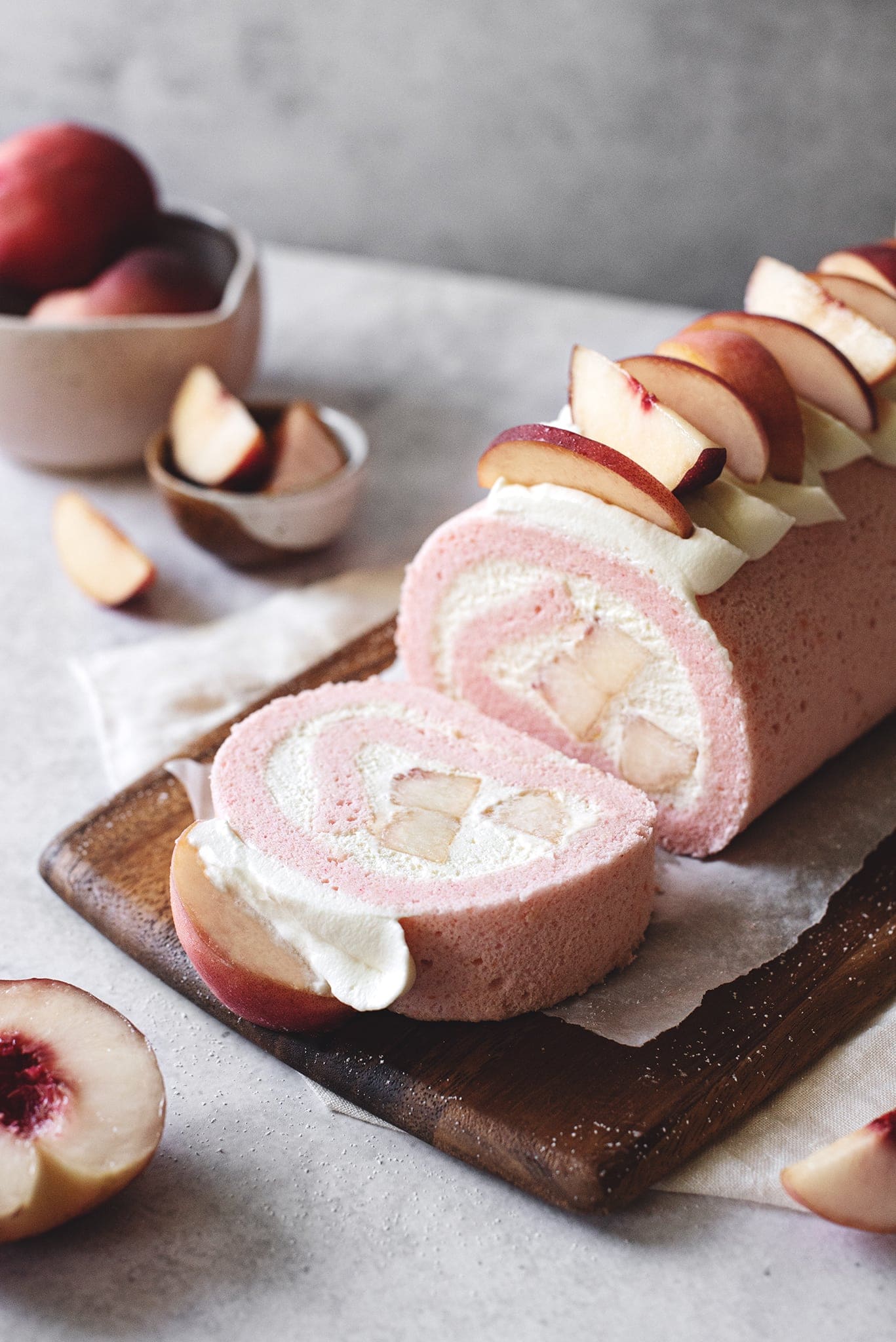 A slice of white peach swiss roll cake cut from the roll
