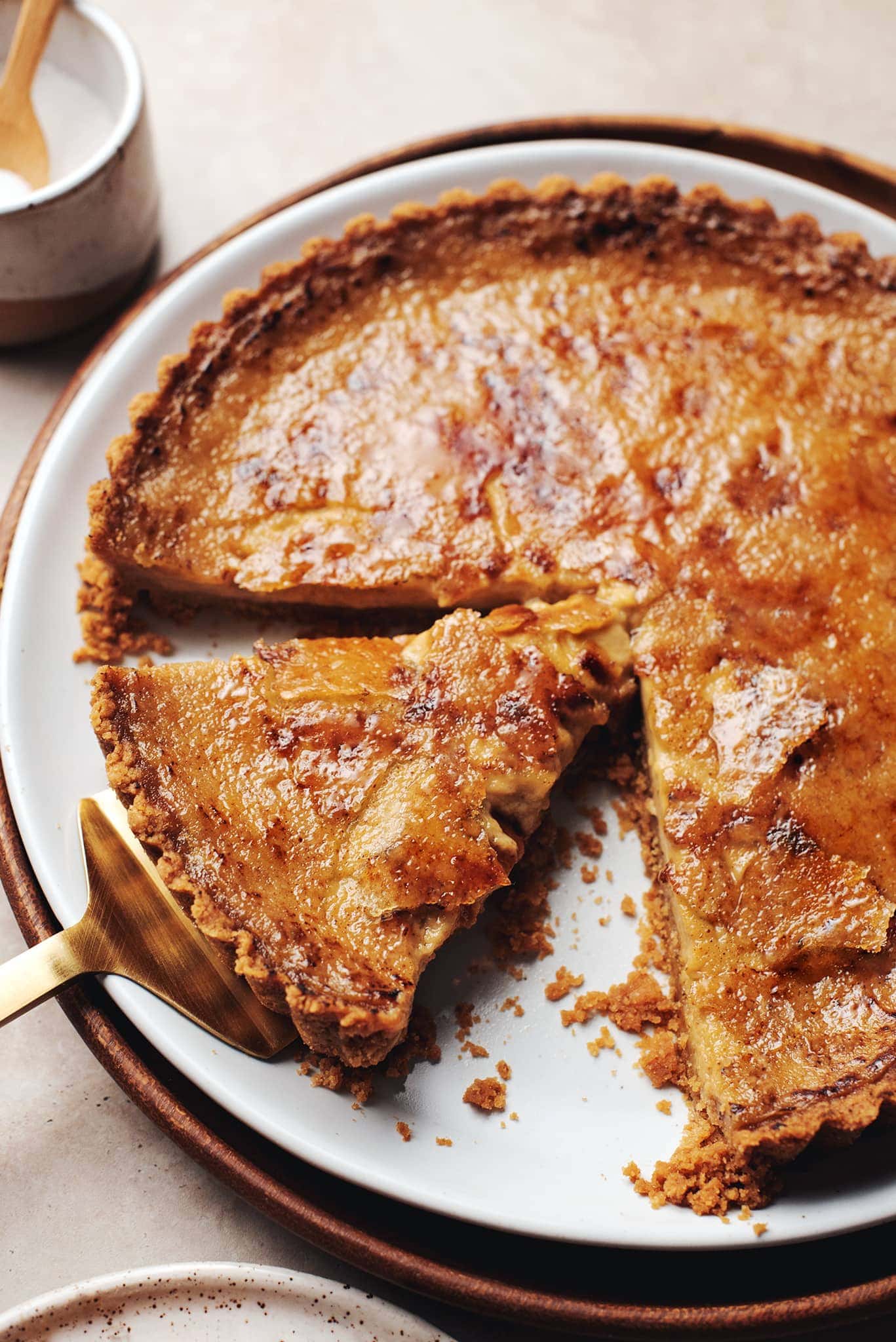 pumpkin crème brûlée tart with a slice cut out of it