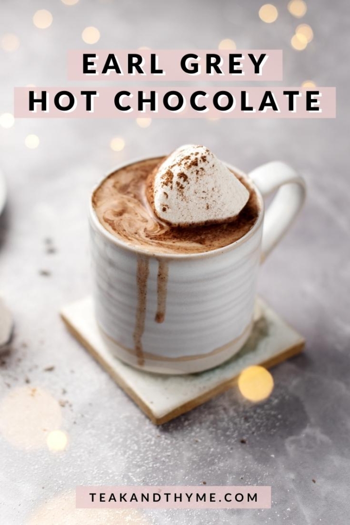 A cup of earl grey hot chocolate topped with a marshmallow and fairy lights in the background