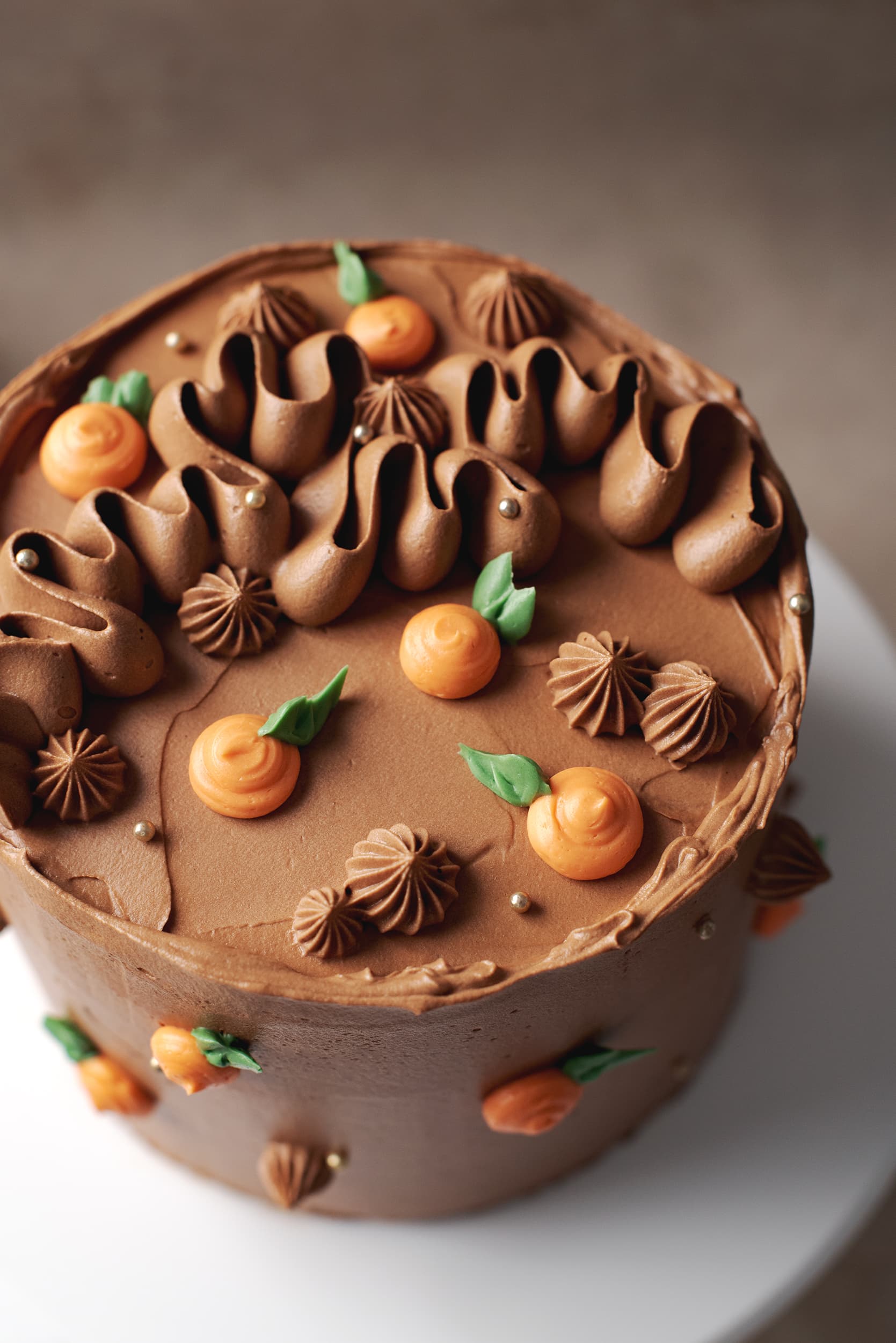 chocolate orange cake decorated with squiggles of chocolate frosting and buttercream oranges