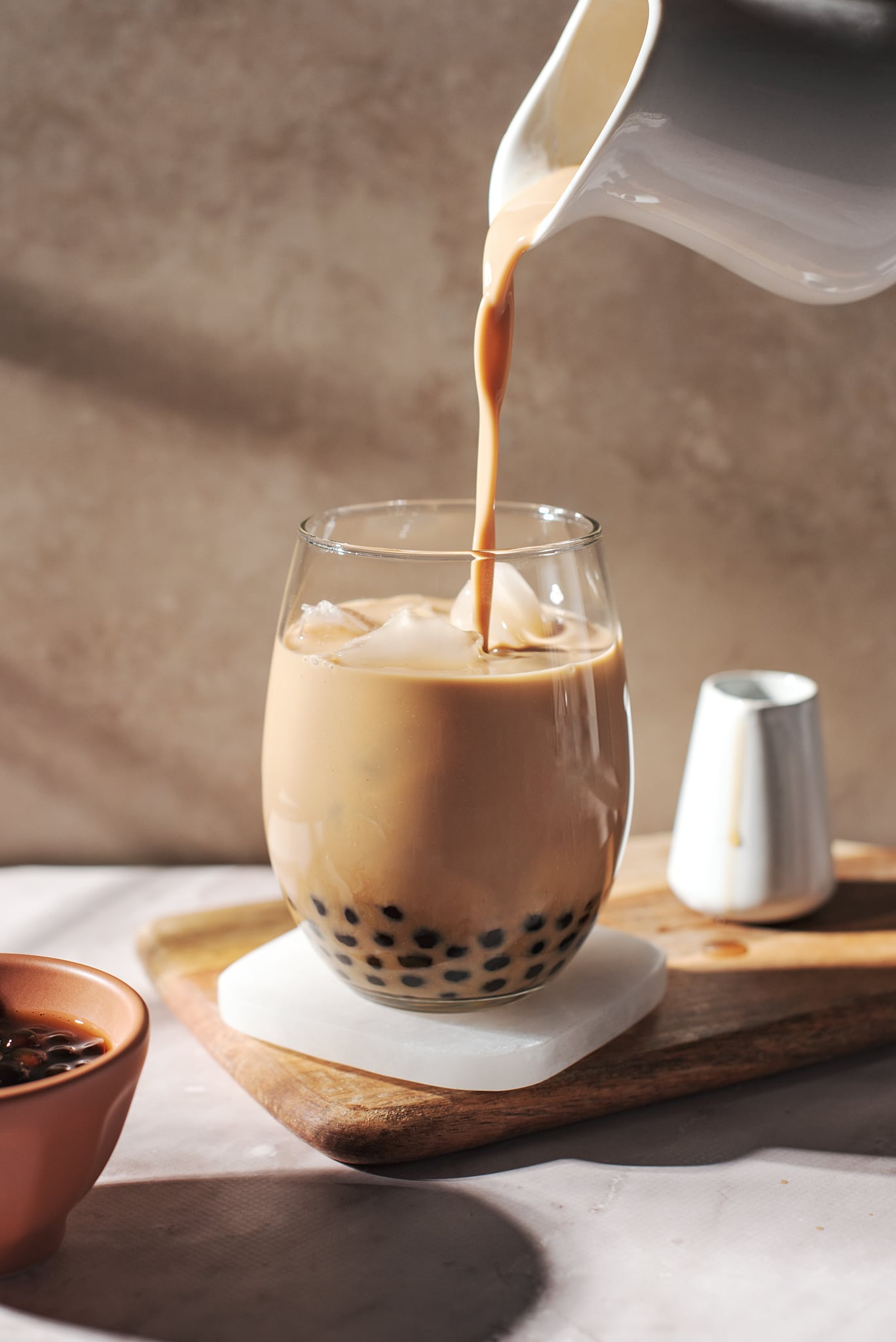 pouring a stream of milk tea into glass