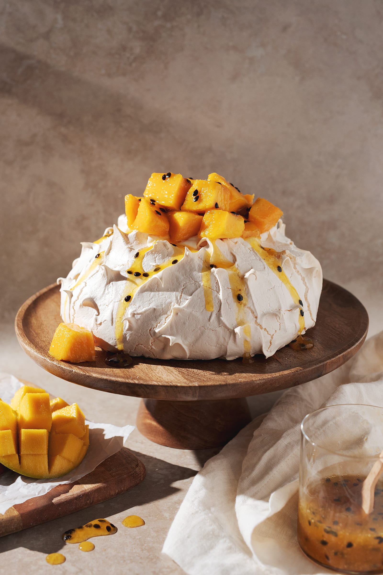 mango passionfruit pavlova on a wooden cake stand
