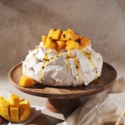 mango passionfruit pavlova on a wooden cake stand