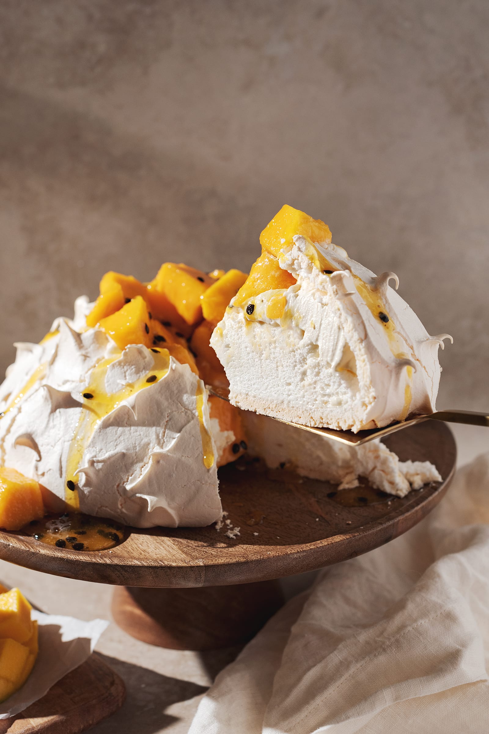 lifting a slice out of mango passionfruit pavlova