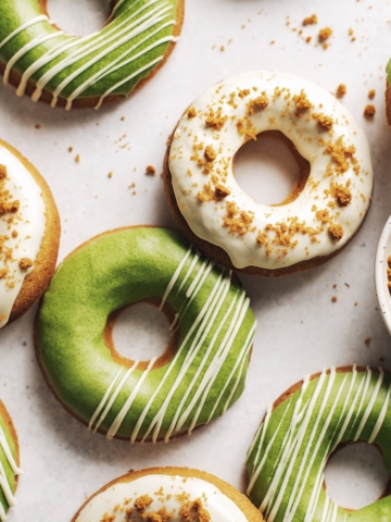 Matcha and white chocolate biscoff mochi donuts scattered on table.