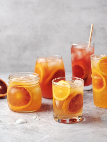 Glasses of blood orange paloma cocktails on grey background