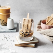 Boba popsicle dipped into cup of milk tea with boba