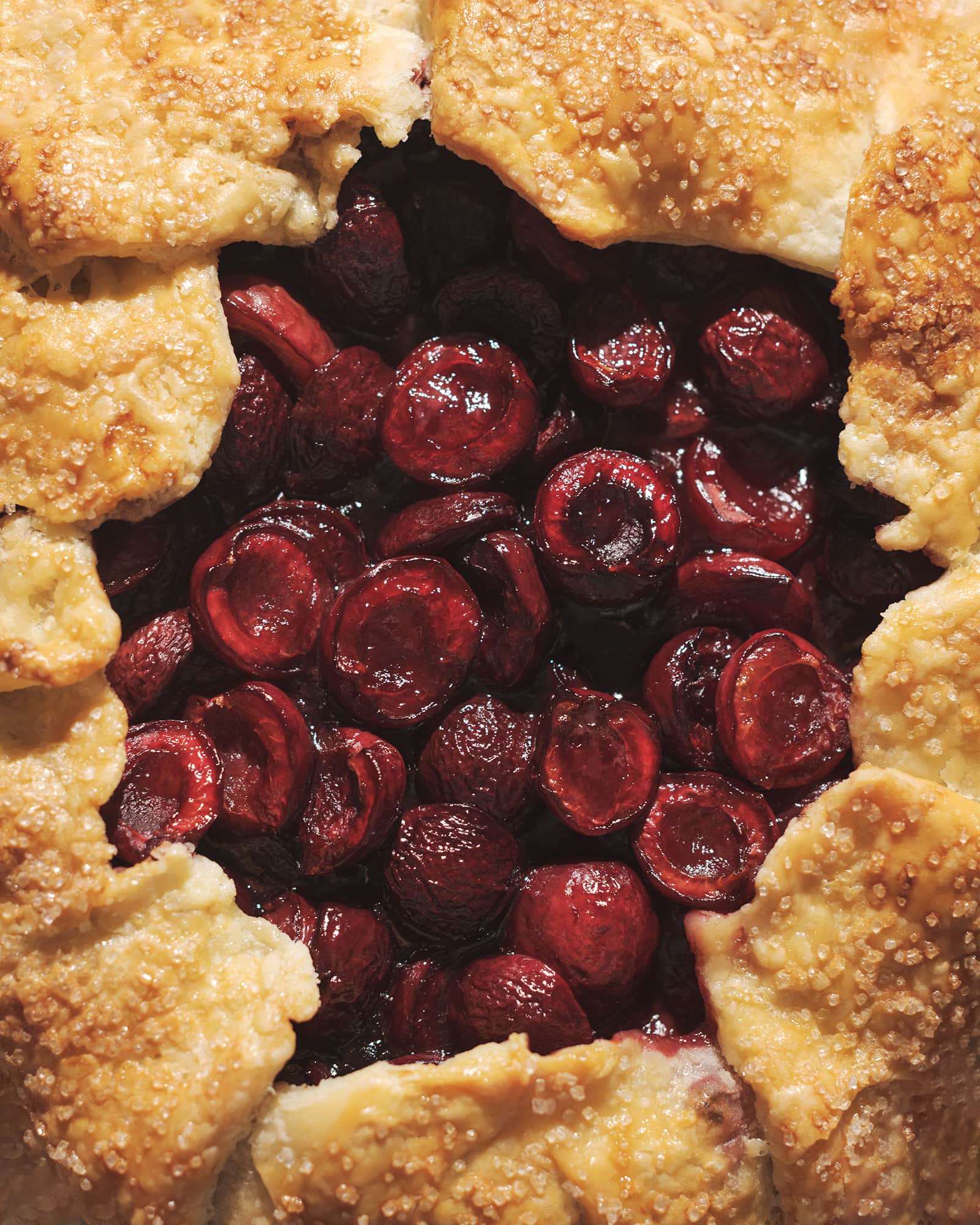 Close up of red cherry filling inside a galette crust.