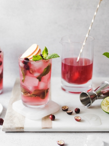 Cranberry apple mojitos on a marble and wood serving tray
