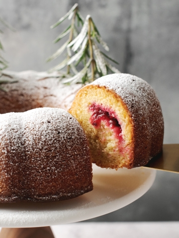a slice of cranberry orange bundt cake lifted by cake server