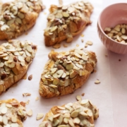 Almond croissants sprinkled with sliced almonds on pink background
