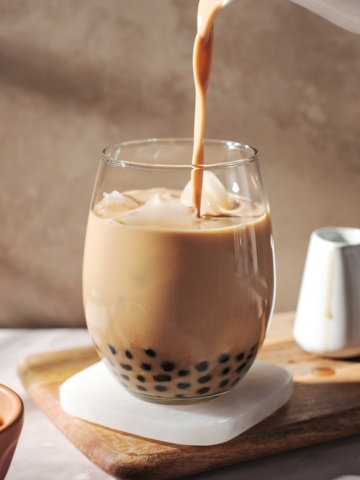 pouring a stream of milk tea into glass