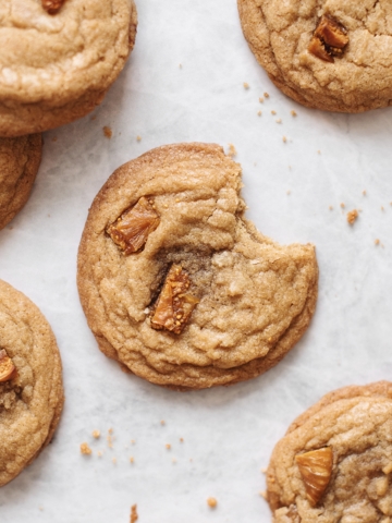 A bite taken out of a cookie surrounded by several cookies