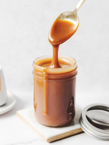 Spoon dripping with caramel sauce above glass jar
